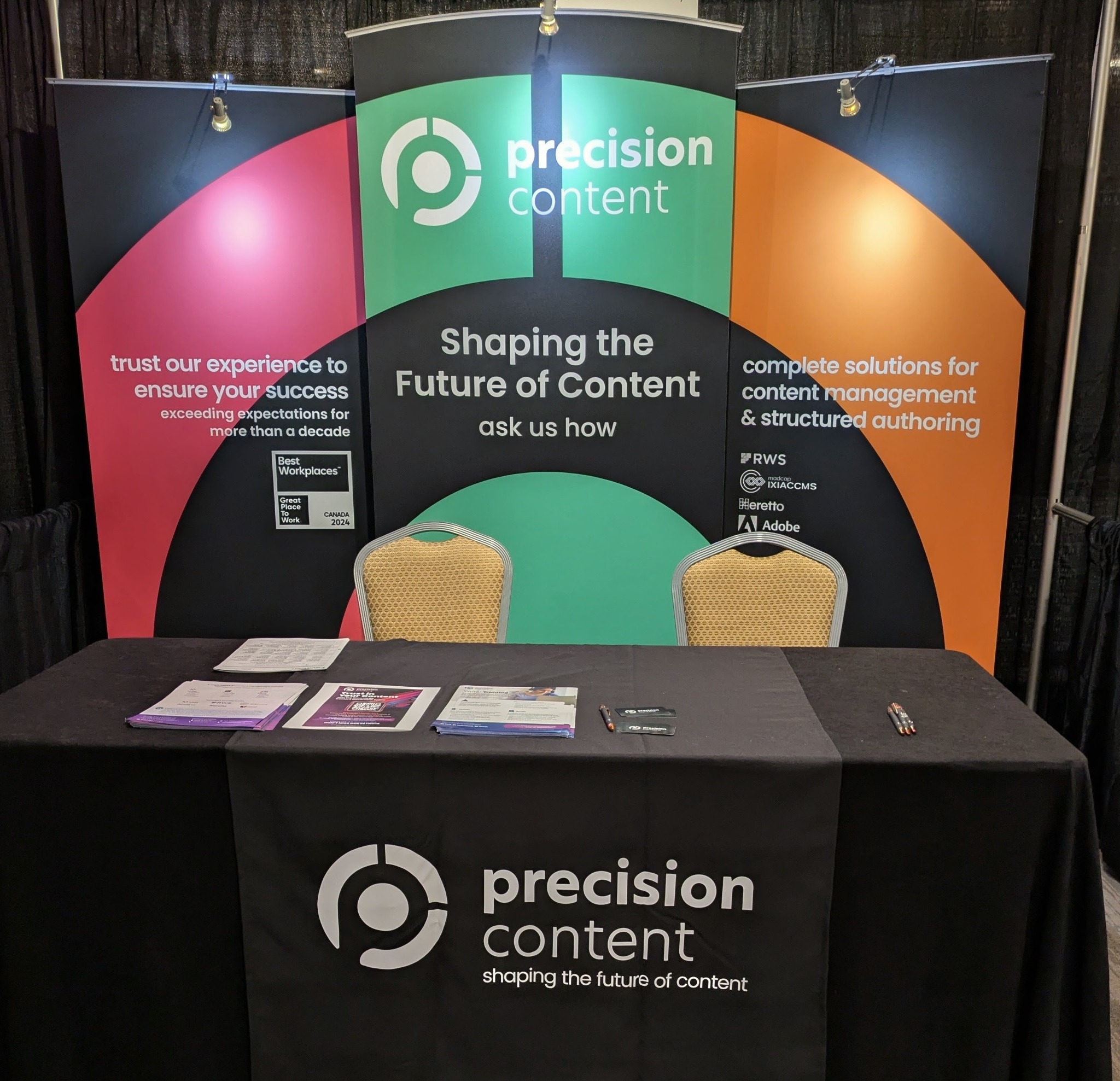 Precision Content conference booth with large rose, green and orange branded panels